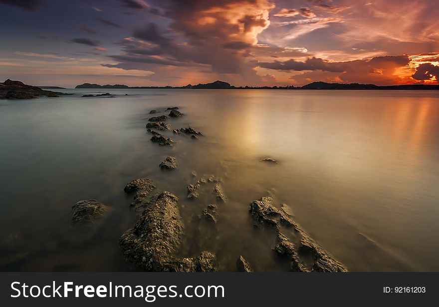 Sunset in cloudy skies over beach on coastline. Sunset in cloudy skies over beach on coastline.