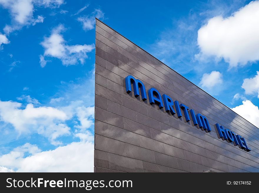 Blue Maritim Hotel signage on building exterior against blue sky with clouds. Blue Maritim Hotel signage on building exterior against blue sky with clouds.
