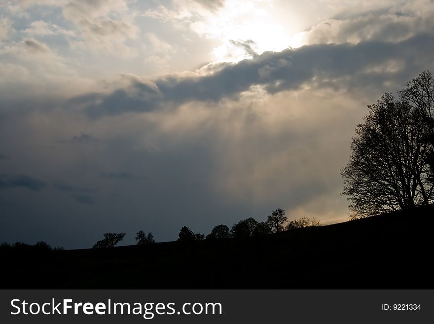 Hill with trees in sunset after storm