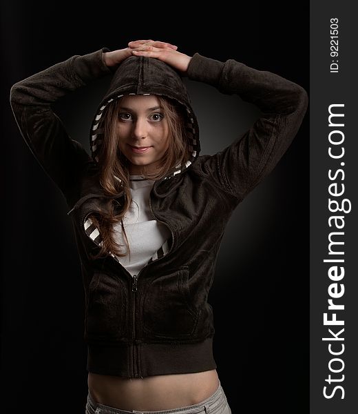 Young girl in hood is smiling against a dark background. Young girl in hood is smiling against a dark background