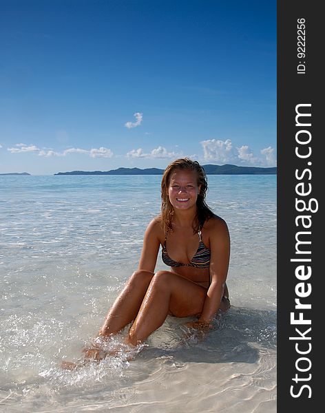 Cute Young Girl Sitting In Water At Beach