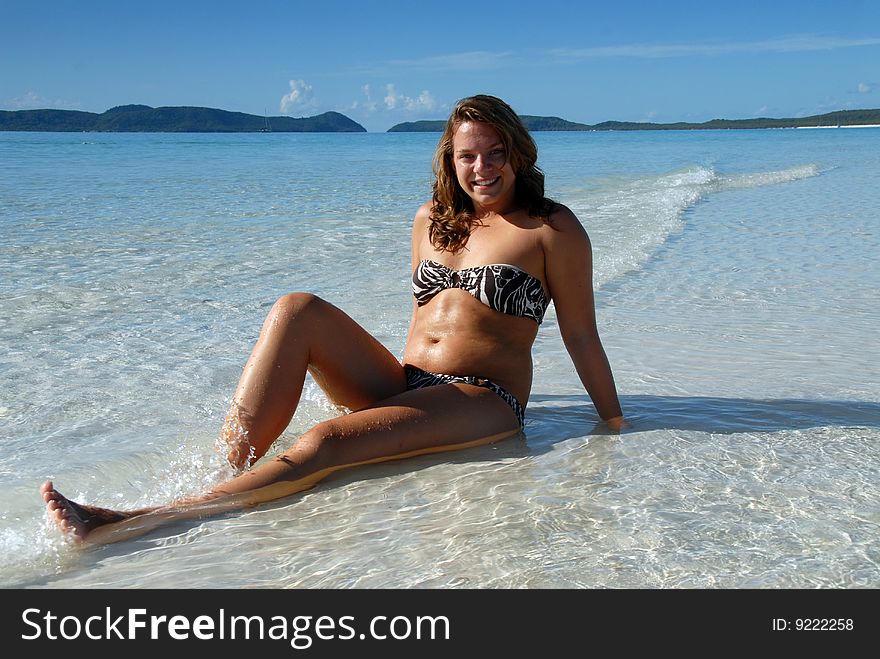 Cute young girl sitting in blue water at paradise beach. Cute young girl sitting in blue water at paradise beach