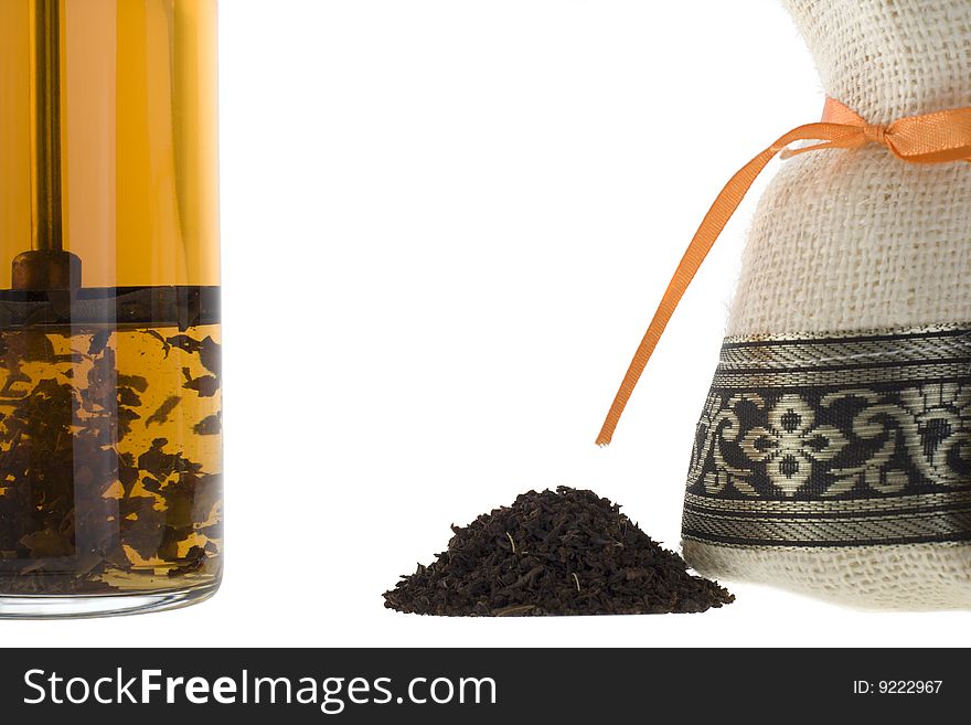 A handful of tea, bag and a glass on a white background.