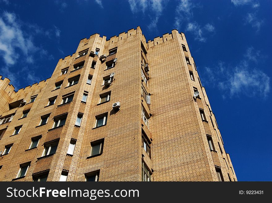 City fortress: yellow multistory brick building on blue sky background