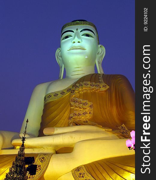 Giant Buddha statue with dramatic sky background.