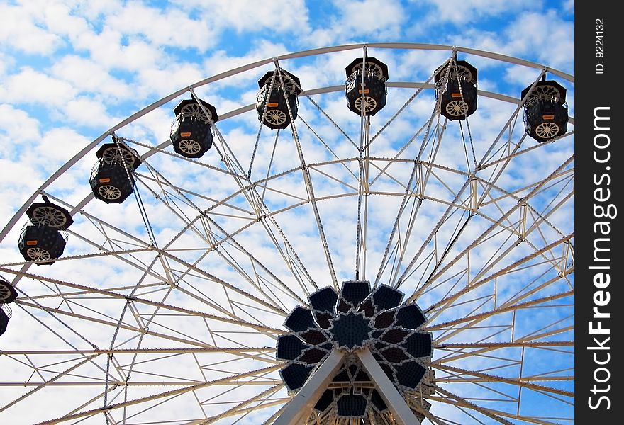 Circling a blue sky full of fluffy white clouds in a ferris wheel.
