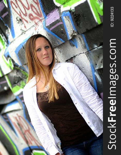 A young woman standing next to a graffiti wall. A young woman standing next to a graffiti wall