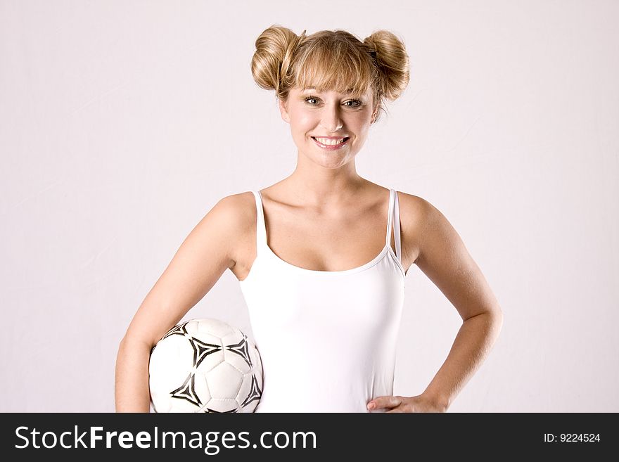 Young blond woman in white sportswear is posing with a football. Young blond woman in white sportswear is posing with a football