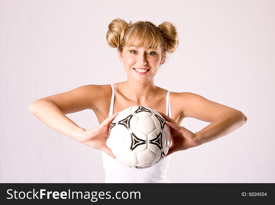 Young blond woman in white sportswear is posing with a football. Young blond woman in white sportswear is posing with a football