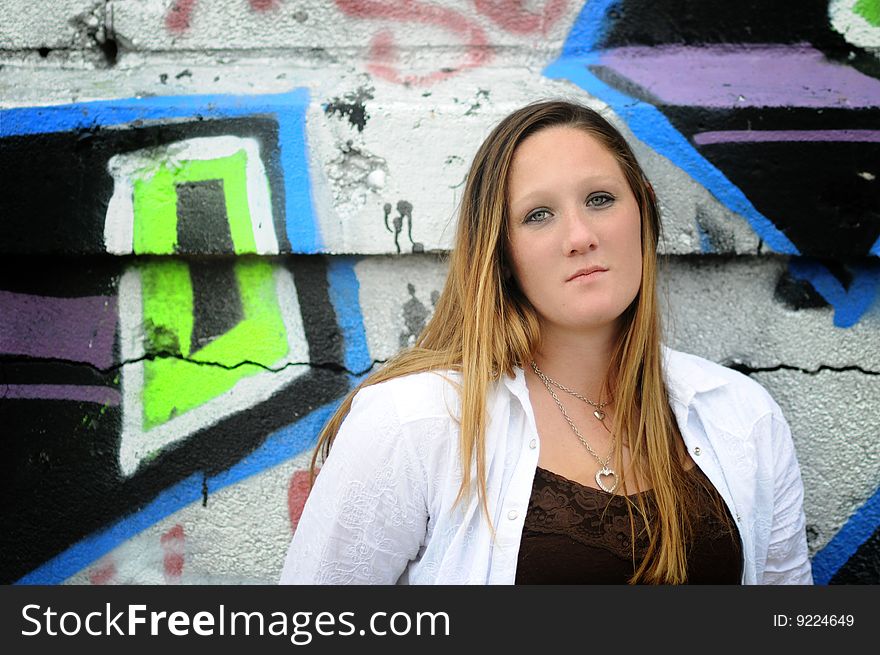 A young woman standing next to a graffiti wall. A young woman standing next to a graffiti wall