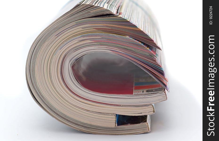 Pile of glossy magazines is curtailed into  roll isolated on white background