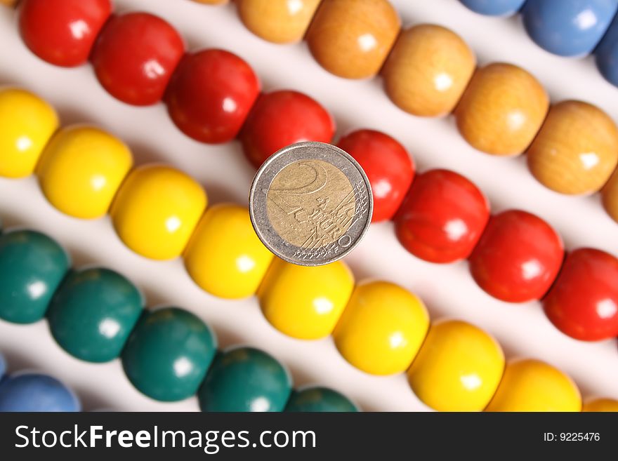Two Euro-coin with unsharp background of an abacus. Two Euro-coin with unsharp background of an abacus