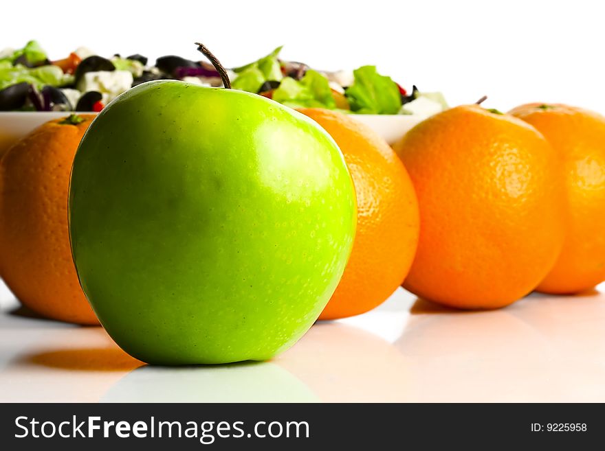 Apple against a background oranges and vegetable salad. Apple against a background oranges and vegetable salad