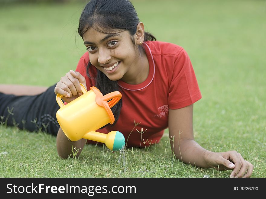 Portrait of beautiful girl lying in garden with watering can