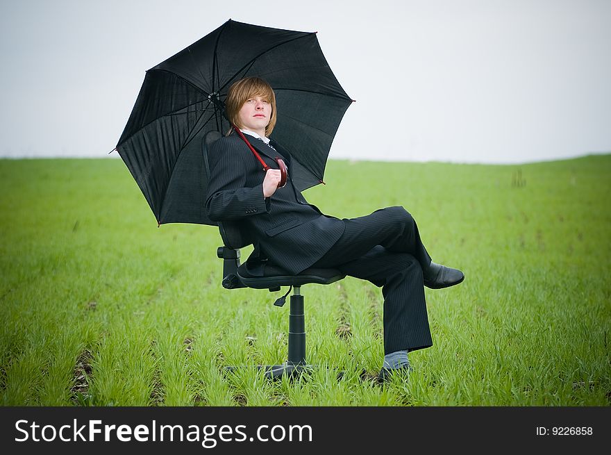 Handsome businessman with umbrella outside - protection concept