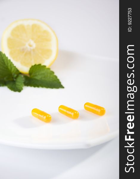 Yellow pills on white plate with lemon