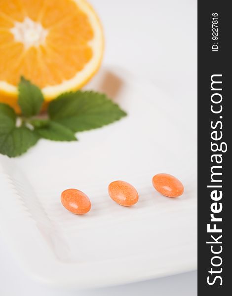 Yellow pills on white plate with orange