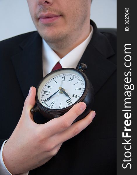 A young attractive businessman holds time in his hand.