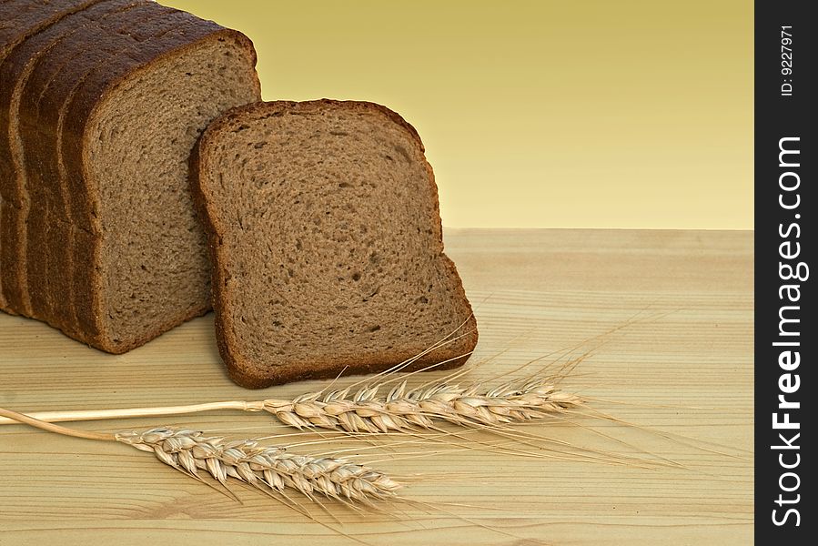 Wheat ears and sliced bread on desk