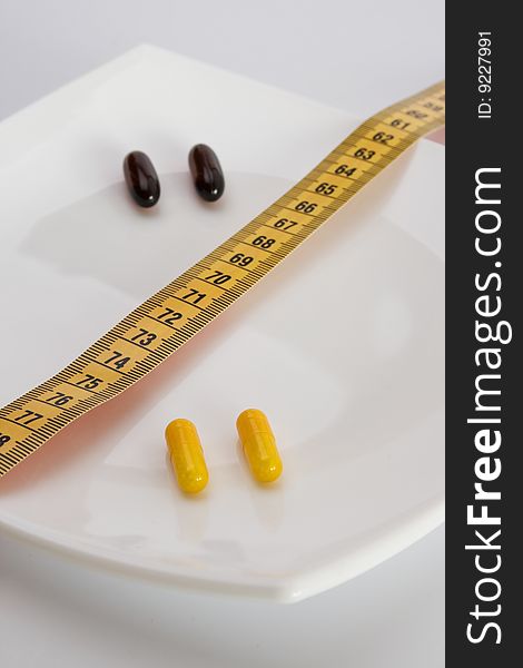 Pills on white plate with tape-measure