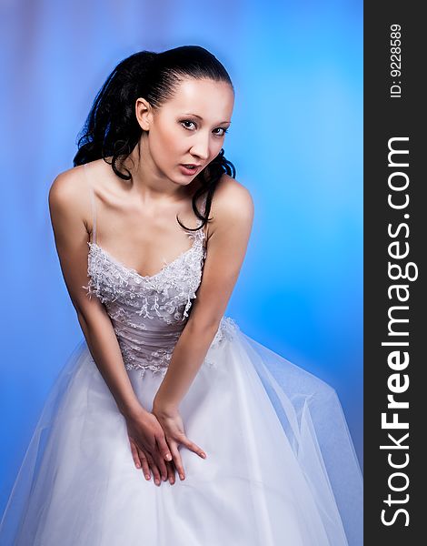 Flirt girl in white wedding dress standing tilted forward