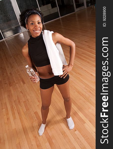 A young african american woman drinks water after a workout. A young african american woman drinks water after a workout