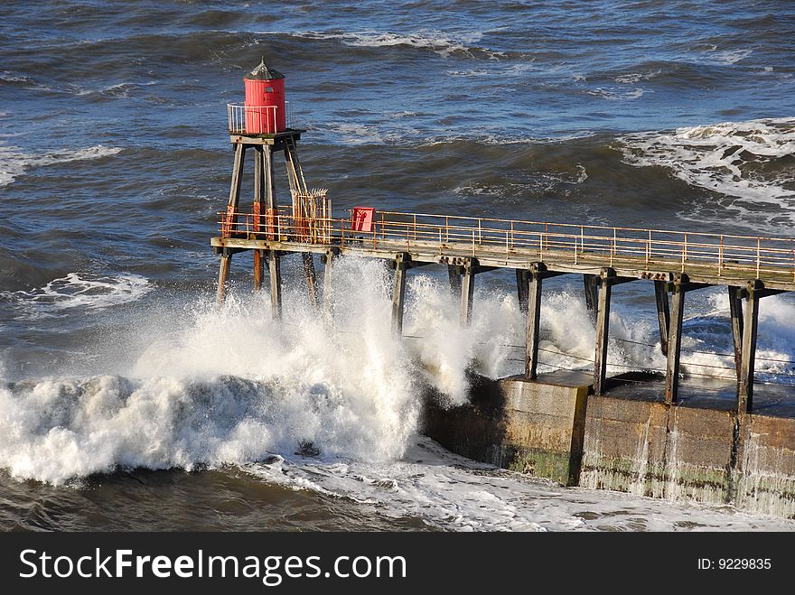 North sea waves crashing over Whitby pier, Yorkshire, England