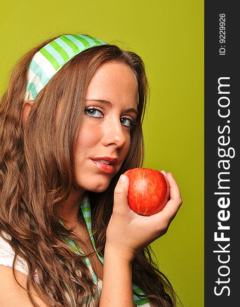 Brunette holding apple against a green background