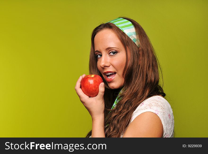 Brunette holding apple against a green background