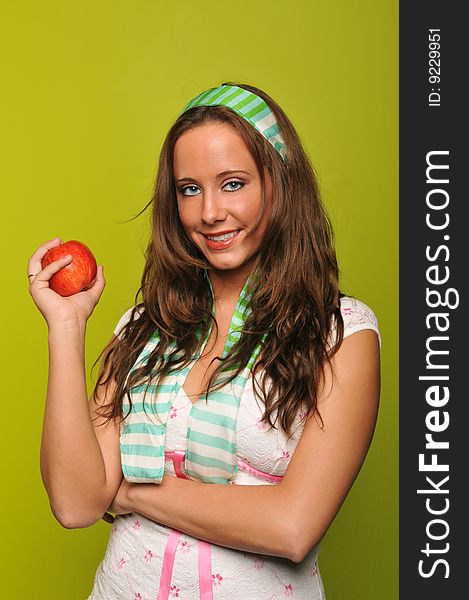 Brunette holding apple and smiling against a green background