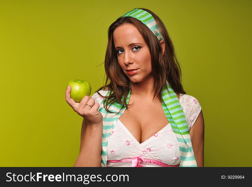 Brunette holding apple against a green background