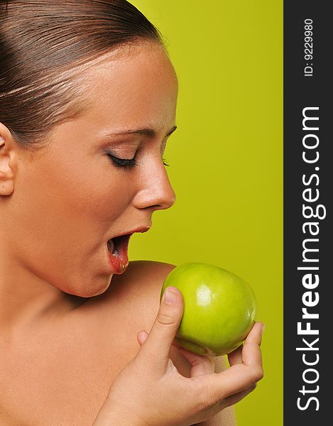 Brunette holding apple against a green background