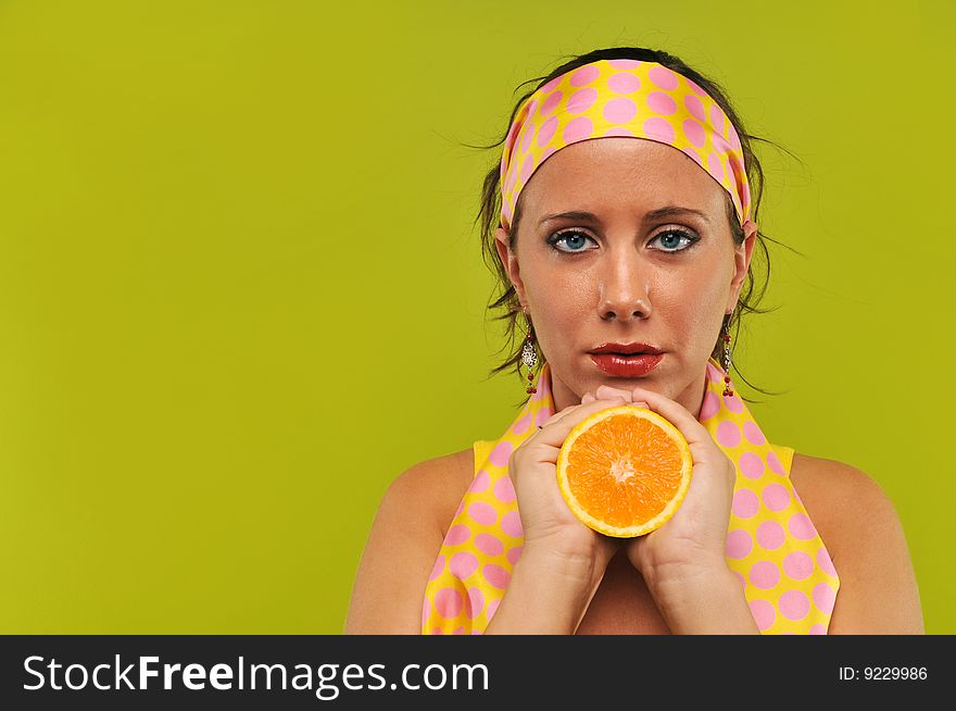 Brunette holding orange against a green background