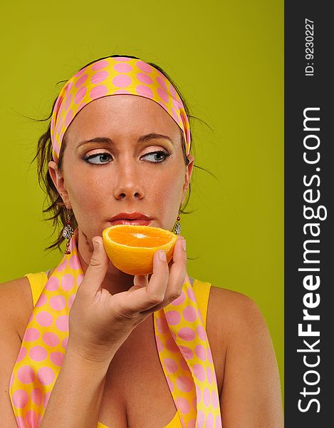 Young woman fashion model holding orange isolated on a green background. Young woman fashion model holding orange isolated on a green background