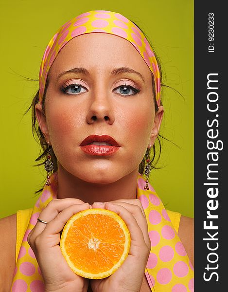 Brunette holding orange against a green background