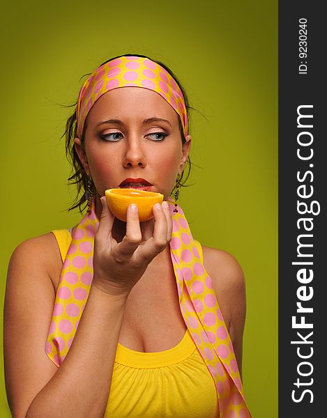 Young woman fashion model holding orange isolated on a green background. Young woman fashion model holding orange isolated on a green background