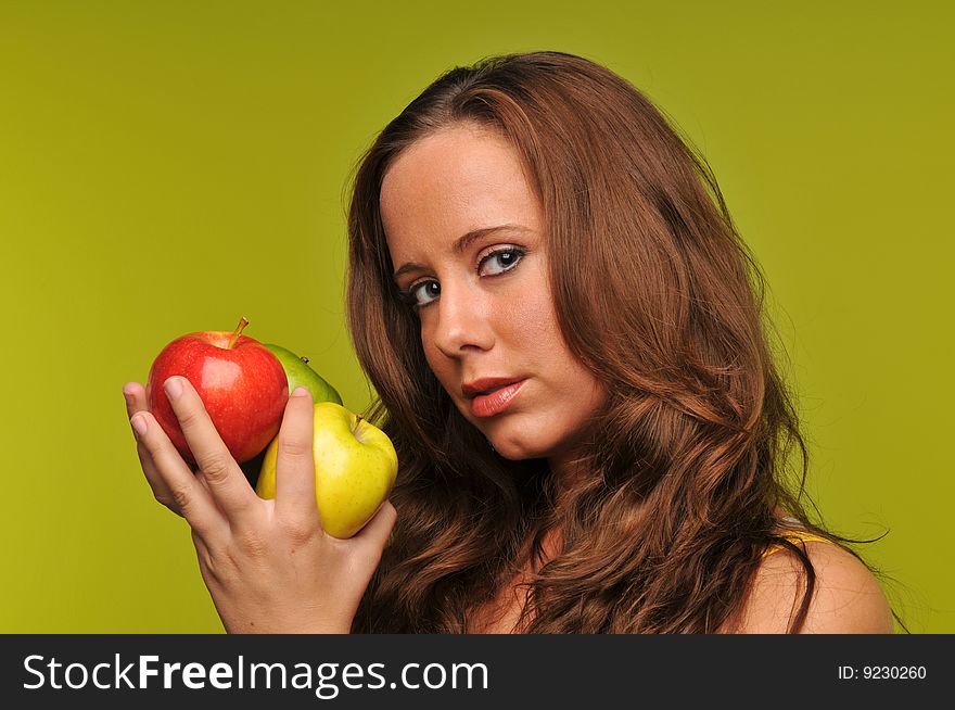 Young woman holding apples isolated against a green background