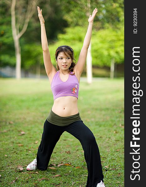 An asian lady is stretching in a yoga pose in a park. An asian lady is stretching in a yoga pose in a park.