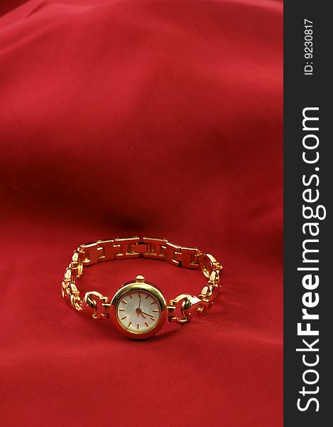 Golden wristwatch on red silk