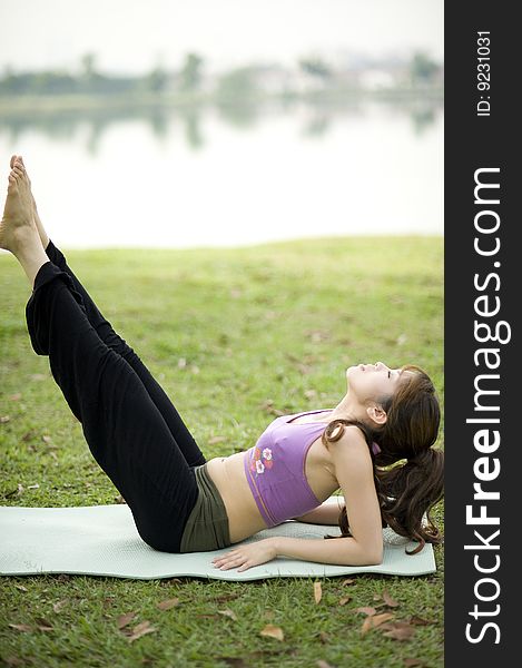 An asian lady is stretching to strengthen the midsection in a park. An asian lady is stretching to strengthen the midsection in a park.