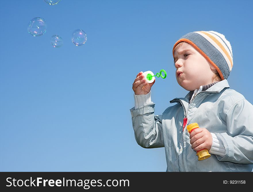 Boy blowing bubbles under blue sky