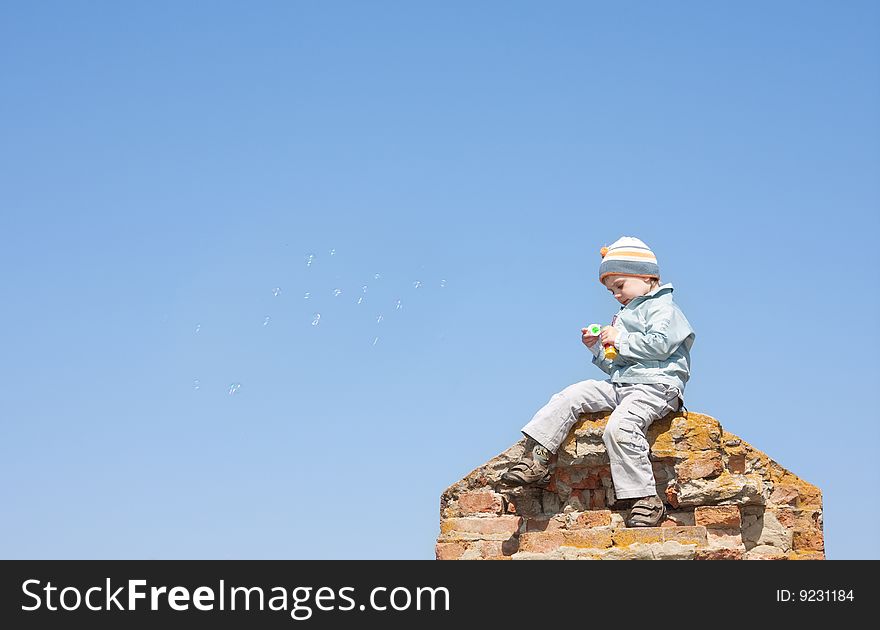 Boy blowing bubbles under the blue sky