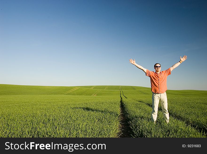 Young men standing on green grass - arms outstretched. Young men standing on green grass - arms outstretched