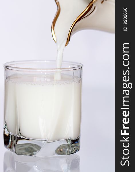 Milk pouring from pitcher into a glass. Milk pouring from pitcher into a glass
