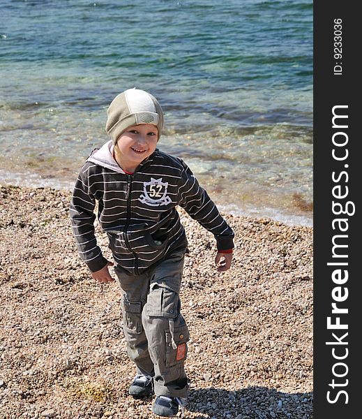 Little boy is jumping on the beach in springtime, he is smiling and happy. Little boy is jumping on the beach in springtime, he is smiling and happy