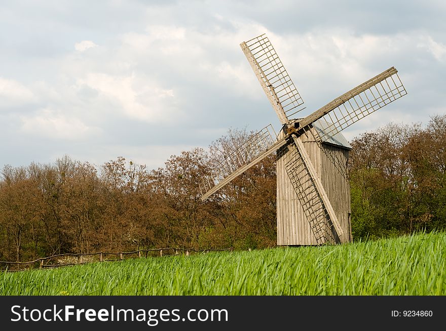 The old windmill to stand on a green field near wood