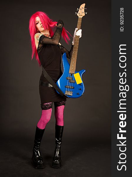 Attractive girl putting on bass guitar, studio shot on black background