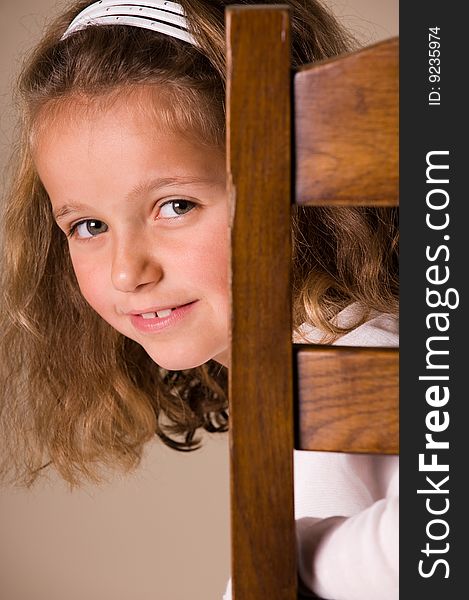 Cute little girl sitting on a chair looking over her shoulder. Cute little girl sitting on a chair looking over her shoulder