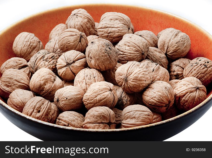 Pile of walnuts in shells in an orange ceramic bowl. Pile of walnuts in shells in an orange ceramic bowl