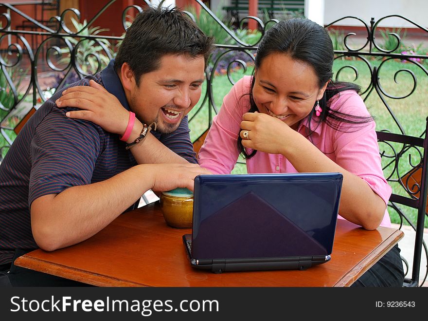 A cute, young HIspanic couple together at a cafe.